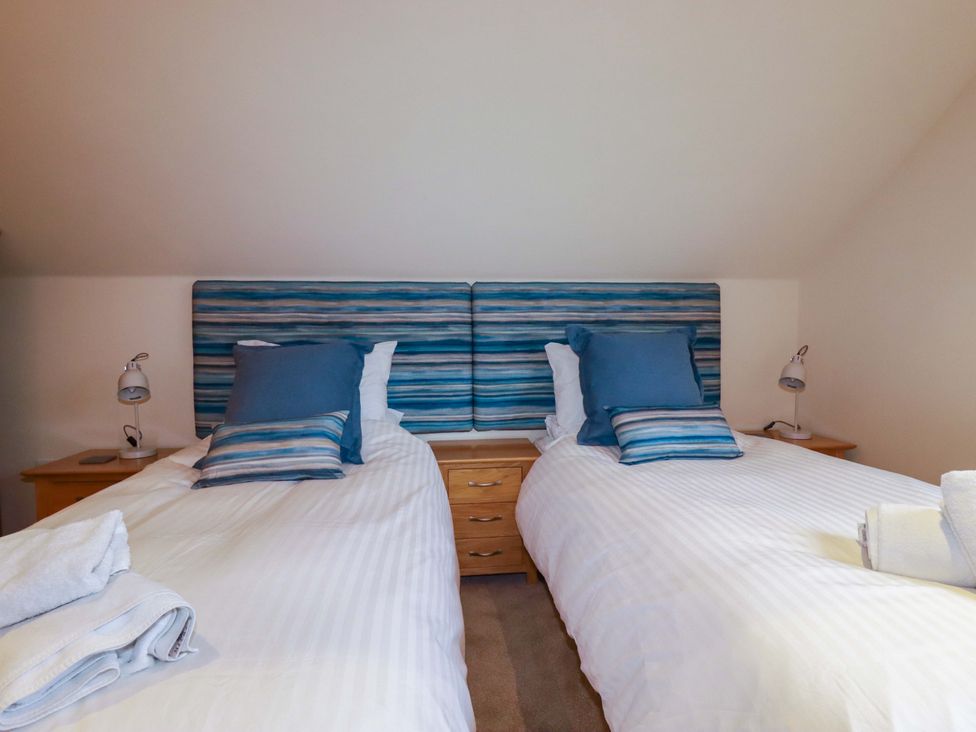 A bedroom with two single beds and a nightstand at 65 Benasa Lodge, Winnard's Perch near St Columb Major