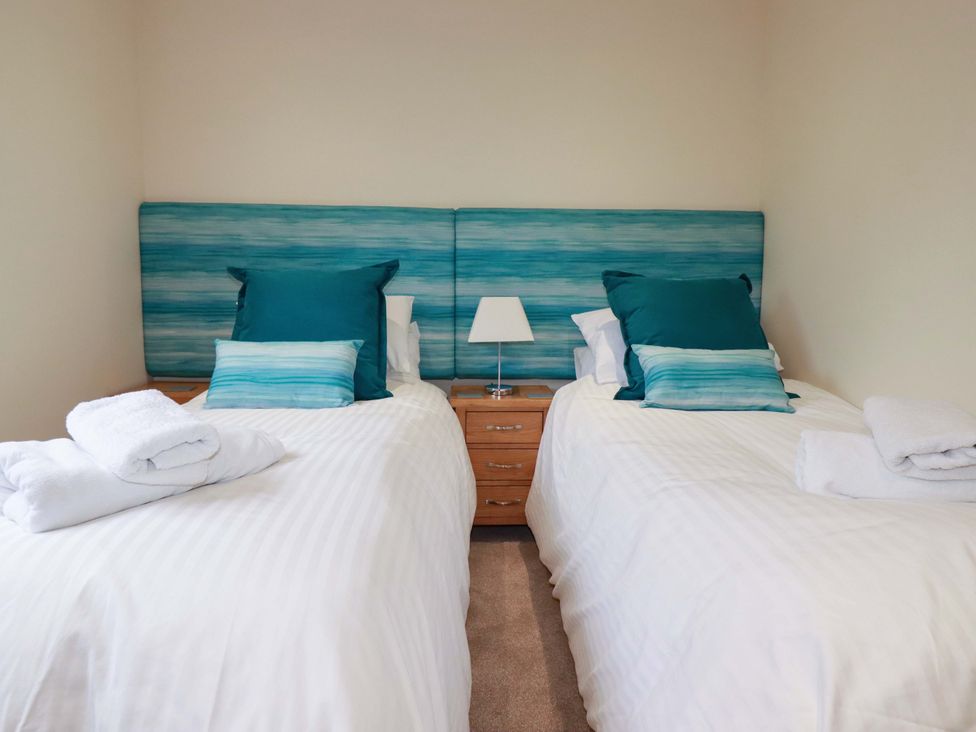 A bedroom with two single beds and a bedside table at 65 Benasa Lodge in Winnard's Perch near St Columb Major