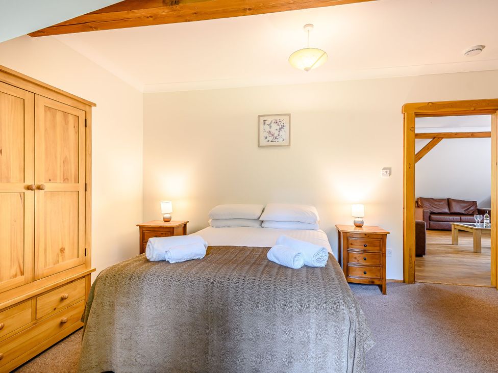 A bedroom with a double bed and wooden furniture at Eagle Spa Plus (Pet) Dundee