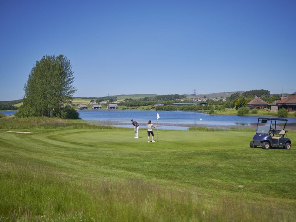 A golf course with players putting near a lake at Eagle Spa Plus (Pet) Dundee