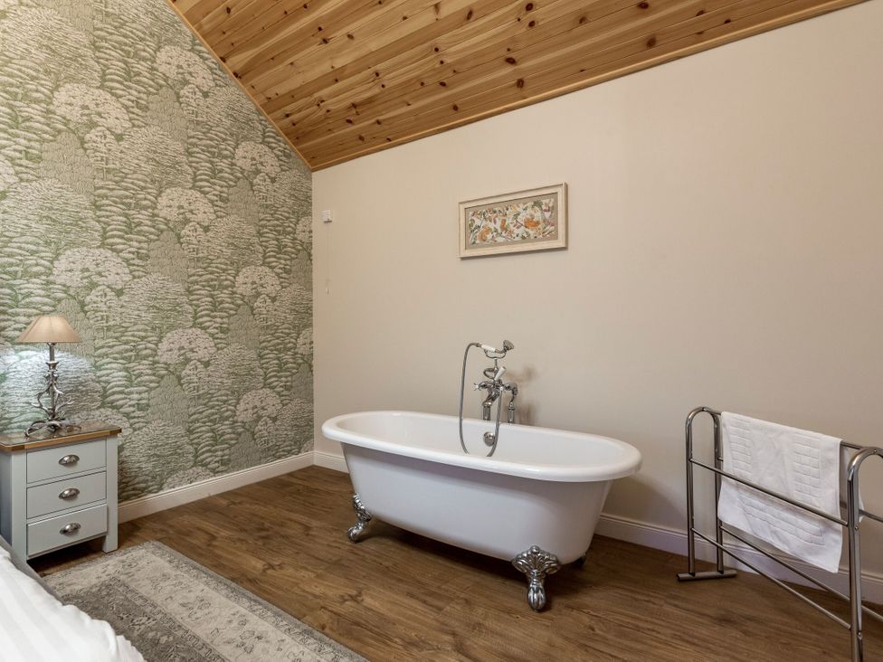 A bathroom with a bathtub and towel rack at Byron Premier Spa in Dundee