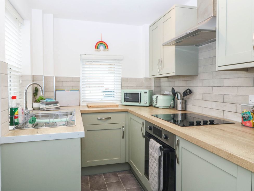 A kitchen with a sink, cabinets, and a microwave at Mona Lodge in Llandudno