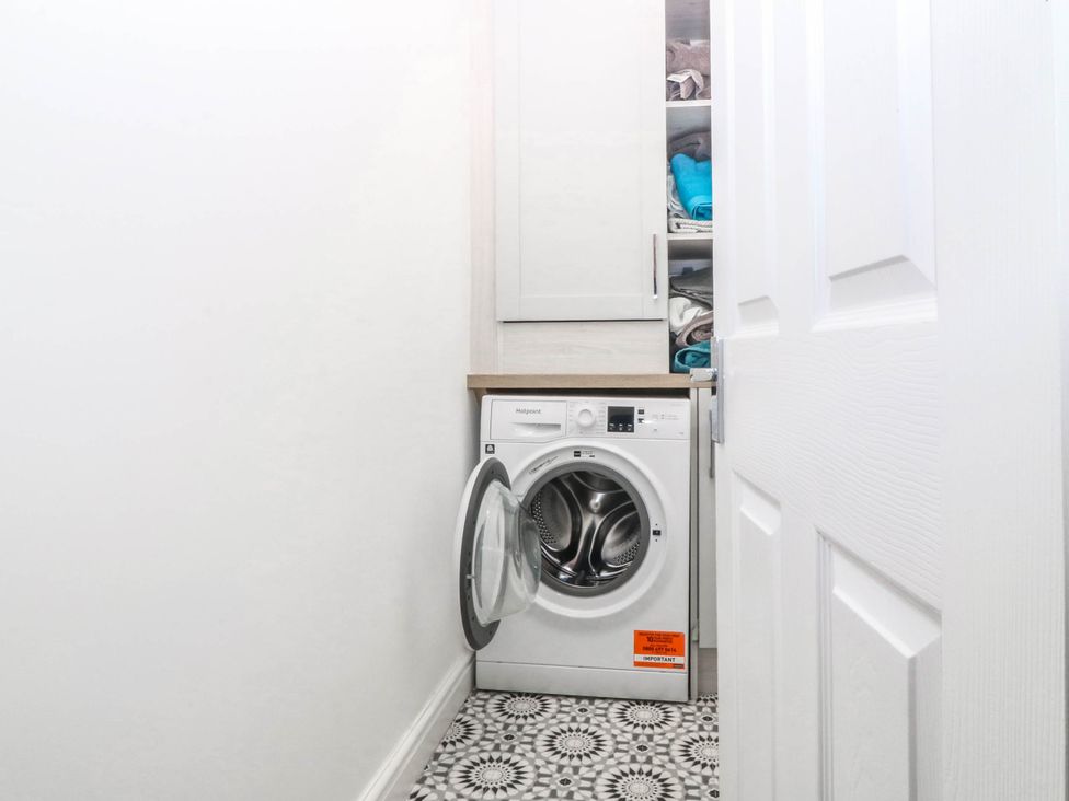 A laundry room with a washing machine and storage cabinet at Mona Lodge in Llandudno