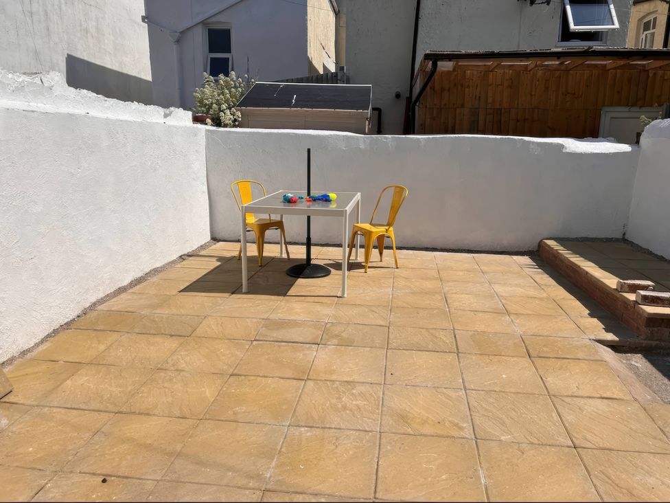 An outdoor patio with a table and yellow chairs at Mona Lodge in Llandudno
