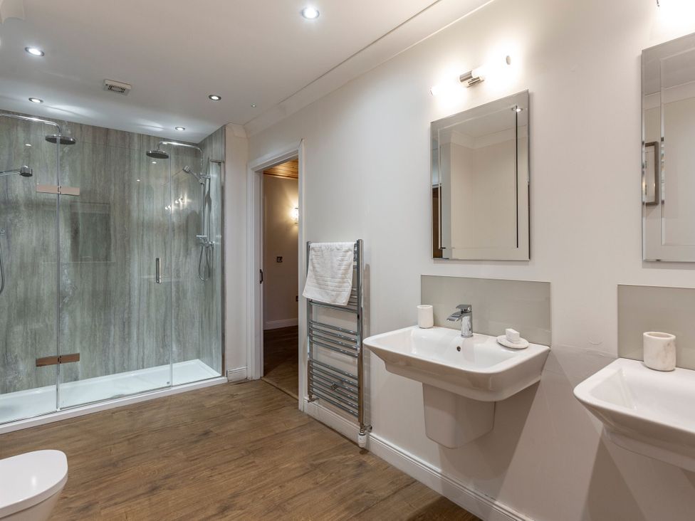 A bathroom with a shower, sinks, and towel rack at Byron Premier Spa (Pet) Dundee