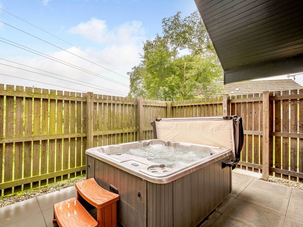 An outdoor area with a hot tub and wooden fence at Muirloch Spa Plus in Dundee