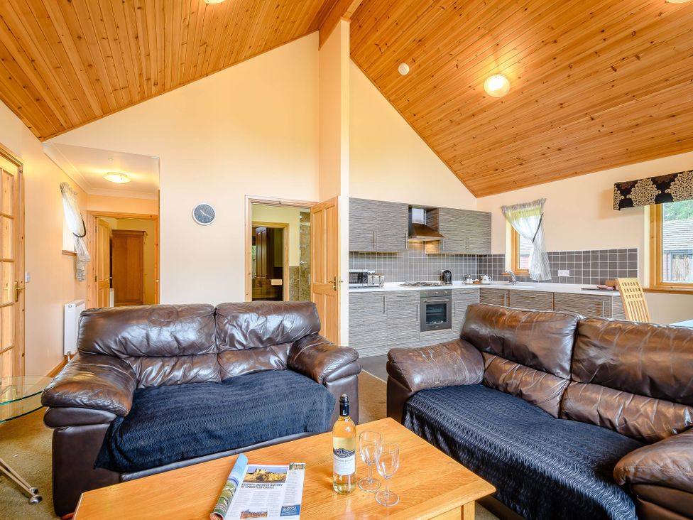 A living room with a sofa and kitchen area at Muirloch Spa Plus in Dundee