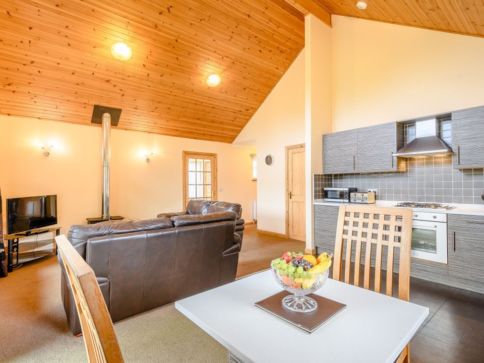 A living room with a sofa and kitchen area at Muirloch Spa Plus in Dundee