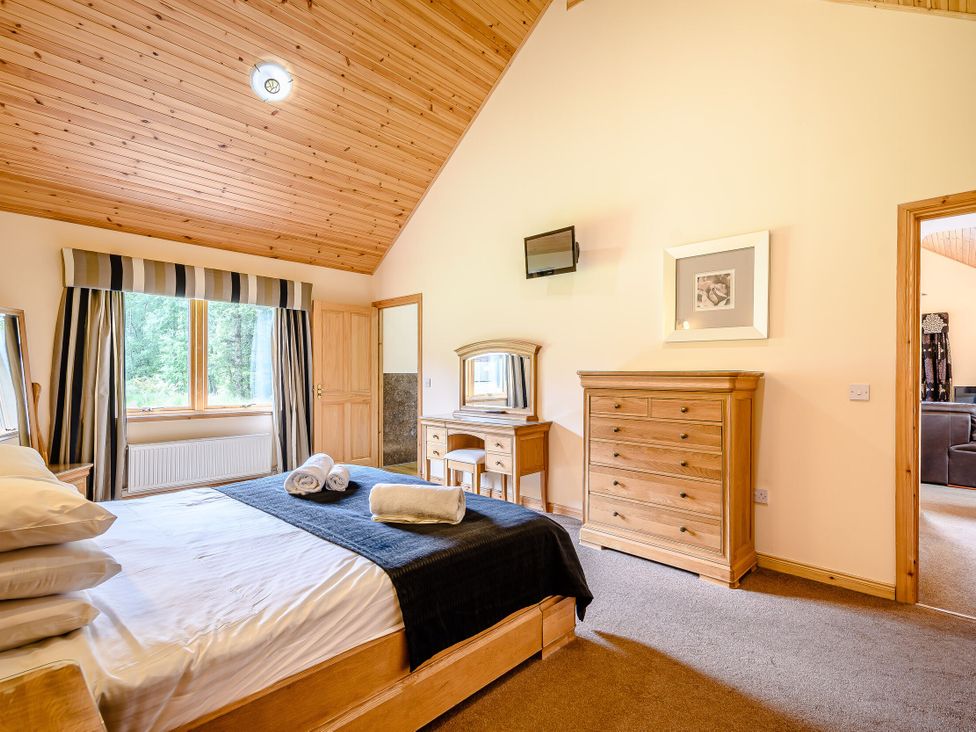 A bedroom with a bed and a wardrobe at Muirloch Spa Plus in Dundee