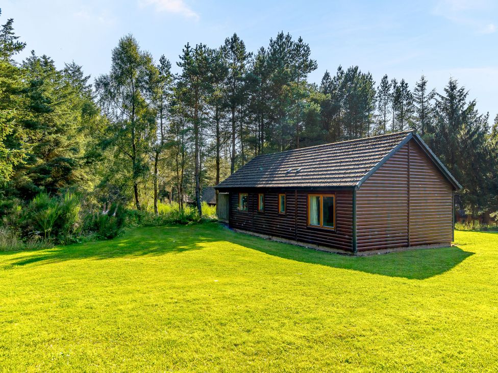 A house surrounded by trees and grass at Muirloch Spa Plus (Pet) in Dundee