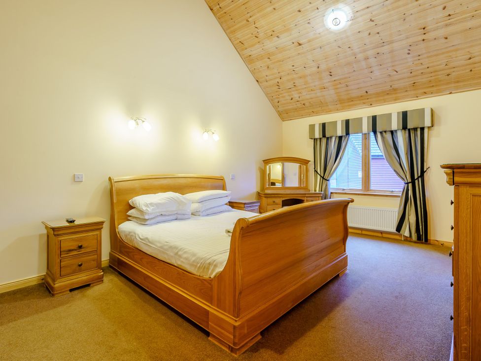 A bedroom with a bed, nightstand, and dresser at Muirloch Spa Plus (Pet) Dundee
