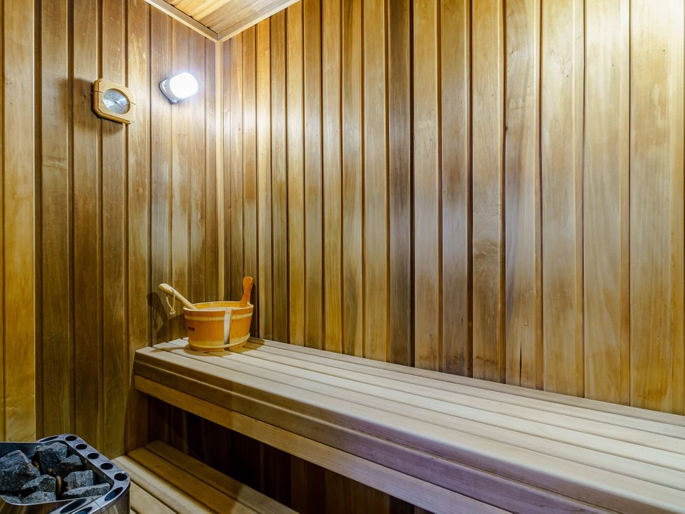 A sauna with wooden benches and a bucket at Muirloch Spa Plus (Pet) Dundee