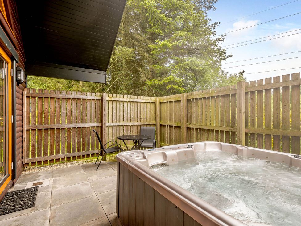 An outdoor area with a hot tub and a table with chairs at Muirloch Spa Plus (Pet) Dundee