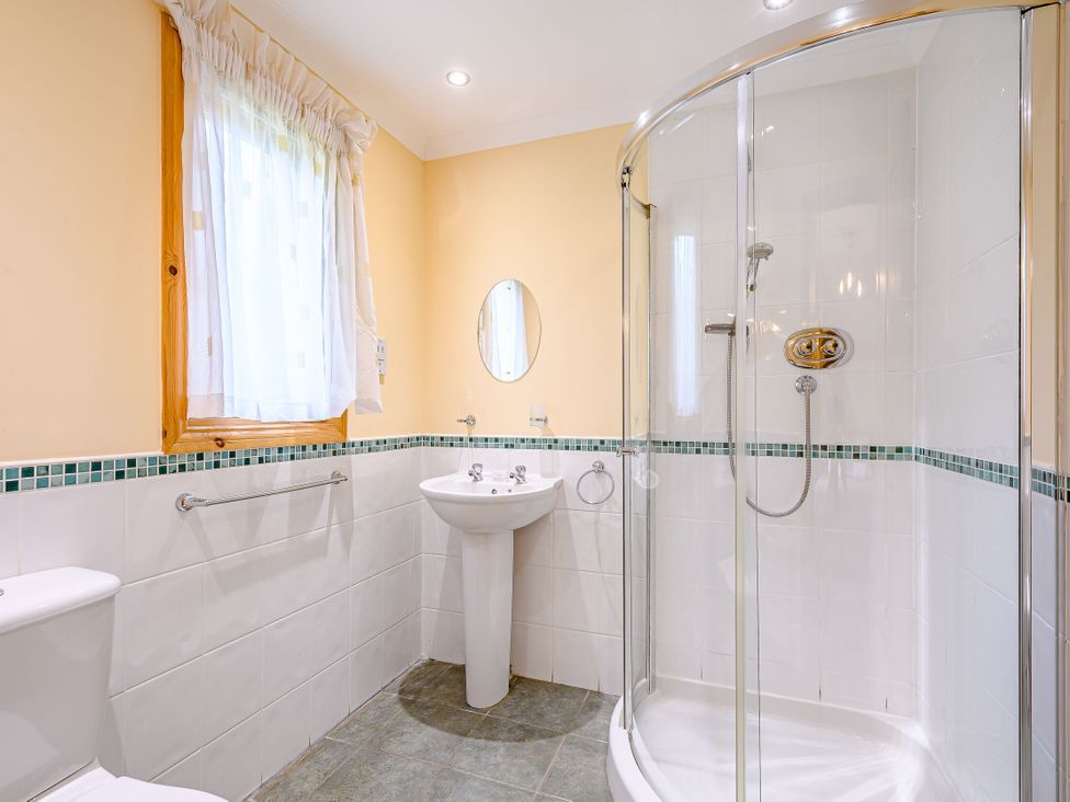 A bathroom with a shower, toilet, sink, and mirror at Rainbow Spa in Dundee