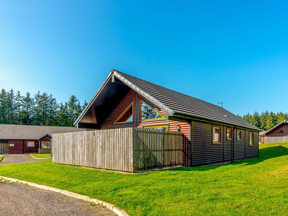 A house with a fence and trees at Rainbow Spa Plus Dundee