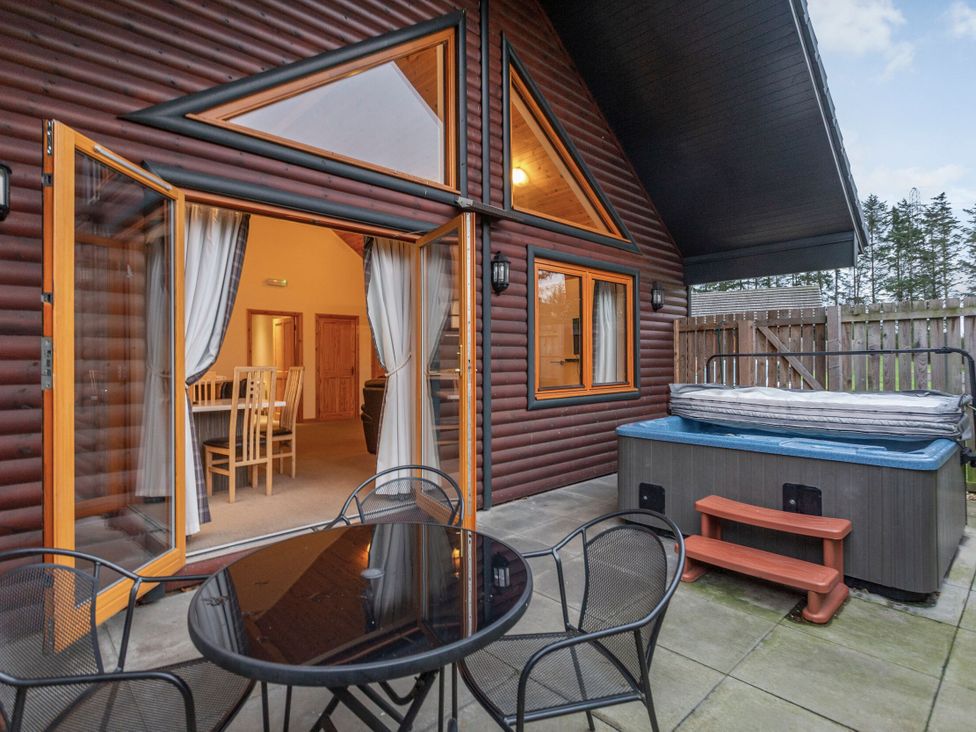 An outdoor area with a table and chairs near a hot tub at Rainbow Spa Plus in Dundee
