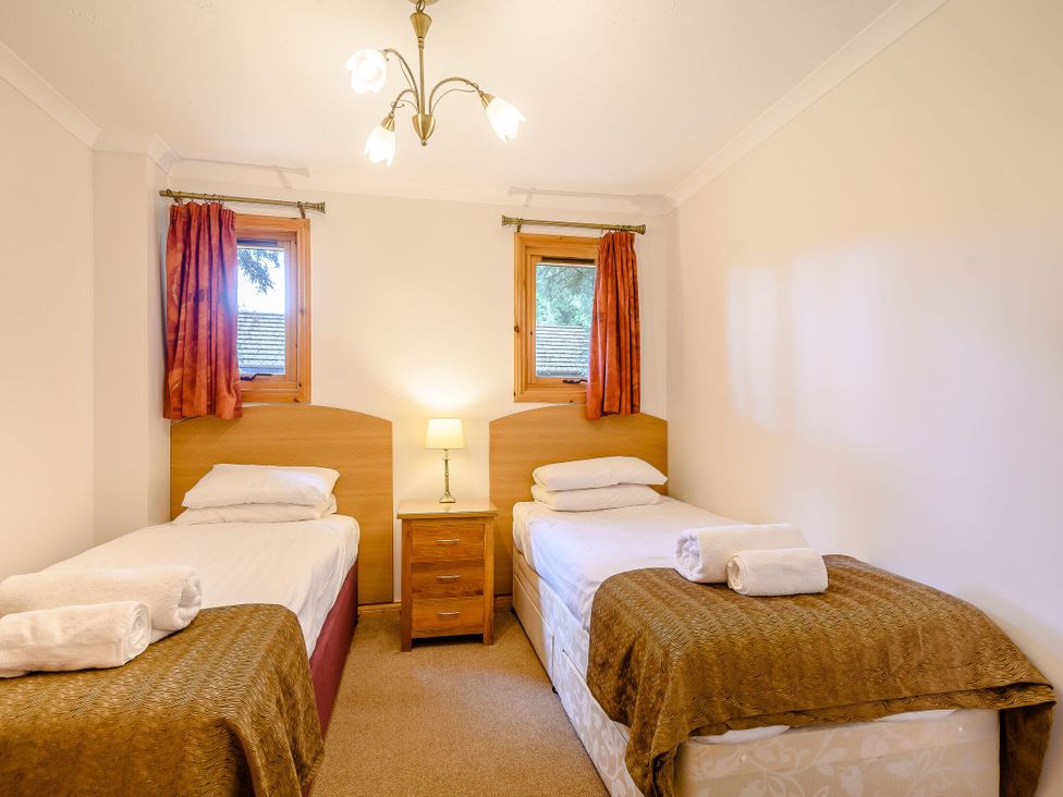 A bedroom with two single beds and a bedside table at Osprey Lodge in Dundee