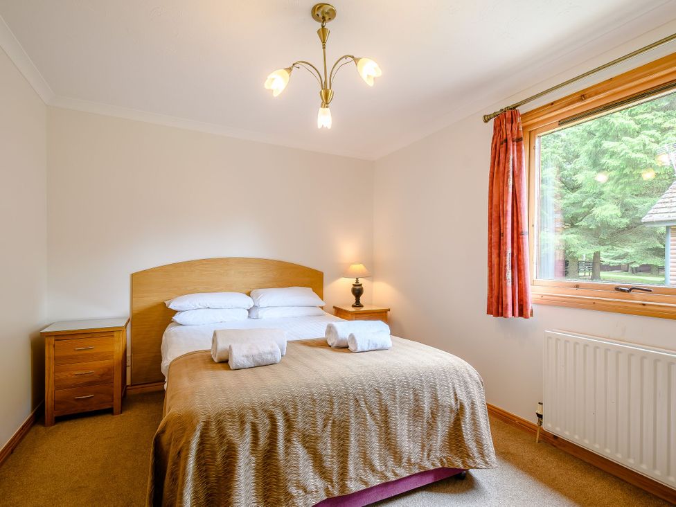 A bedroom with a bed and nightstand at Osprey Lodge in Dundee