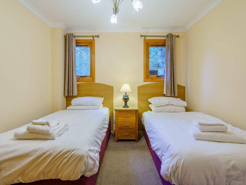 A bedroom with two beds and a bedside table at Osprey Lodge (Pet) Dundee