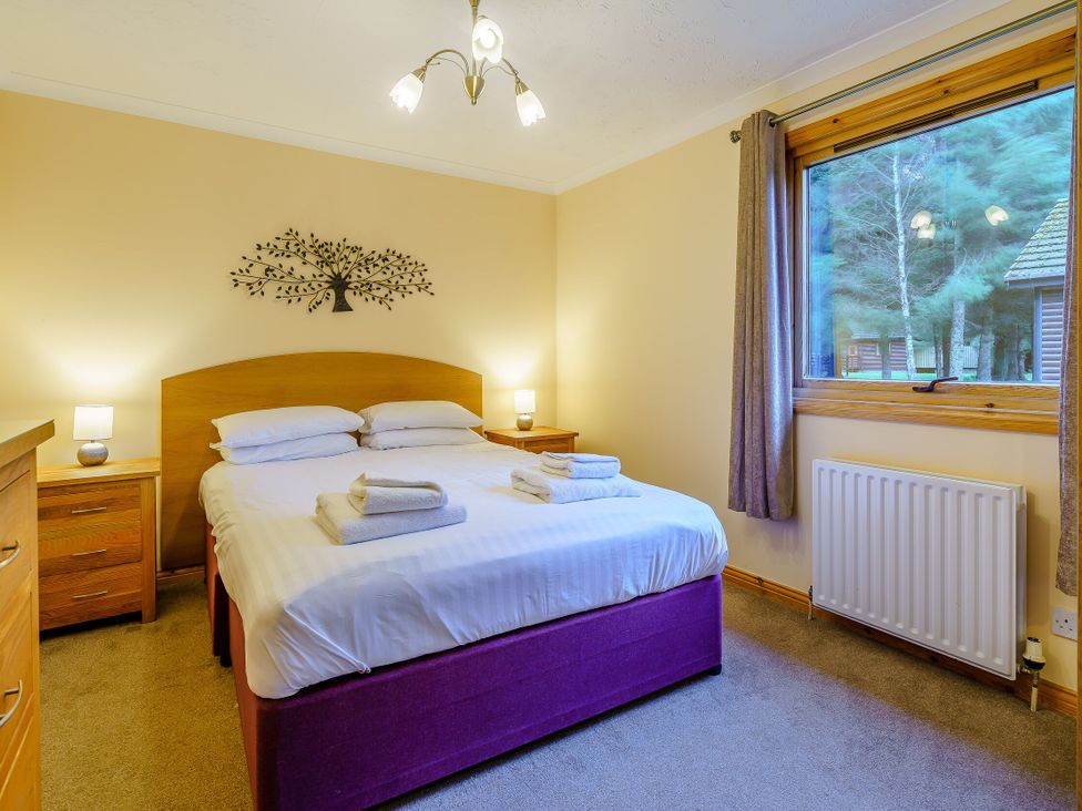 A bedroom with a bed and bedside tables at Osprey Lodge (Pet) Dundee