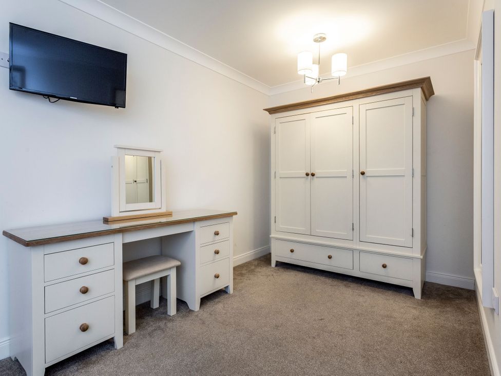 A bedroom with a vanity table and an armoire at Galbraith Premier Spa in Dundee