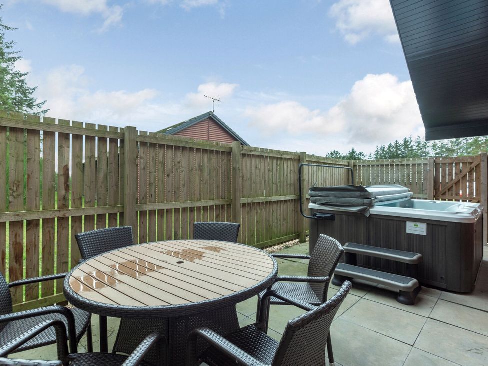 An outdoor area with a table and chairs next to a hot tub at Galbraith Premier Spa (Pet) in Dundee
