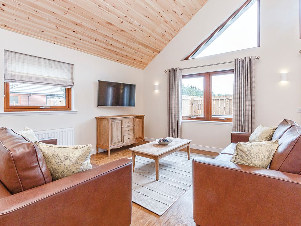 A living room with a sofa, table, and television at Galbraith Premier Spa (Pet) in Dundee