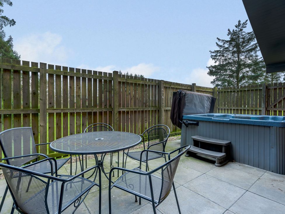 An outdoor area with a hot tub and a table with chairs at Osprey Spa Plus in Dundee