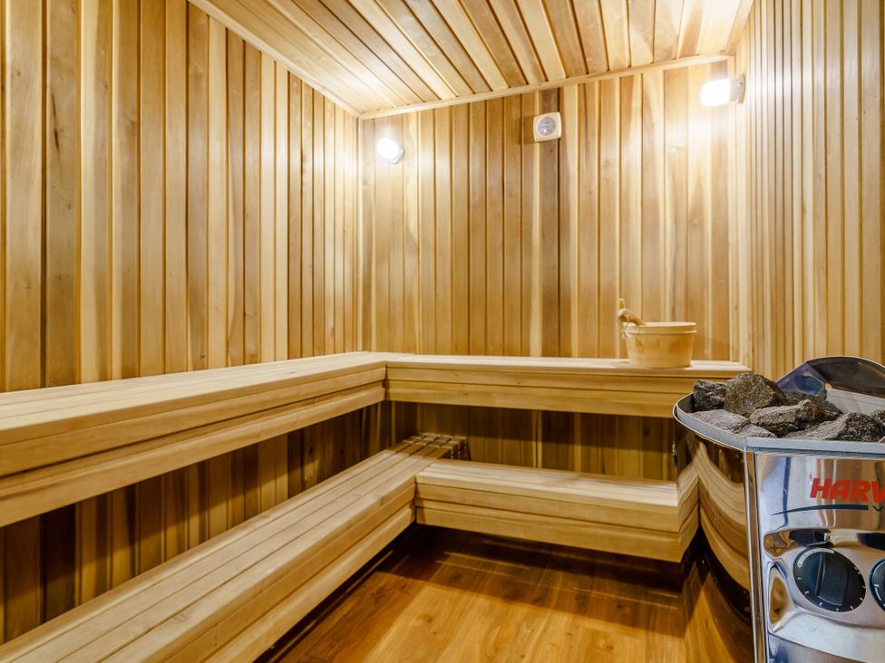 A sauna with wooden benches and a stove containing heated stones at Osprey Spa Plus in Dundee