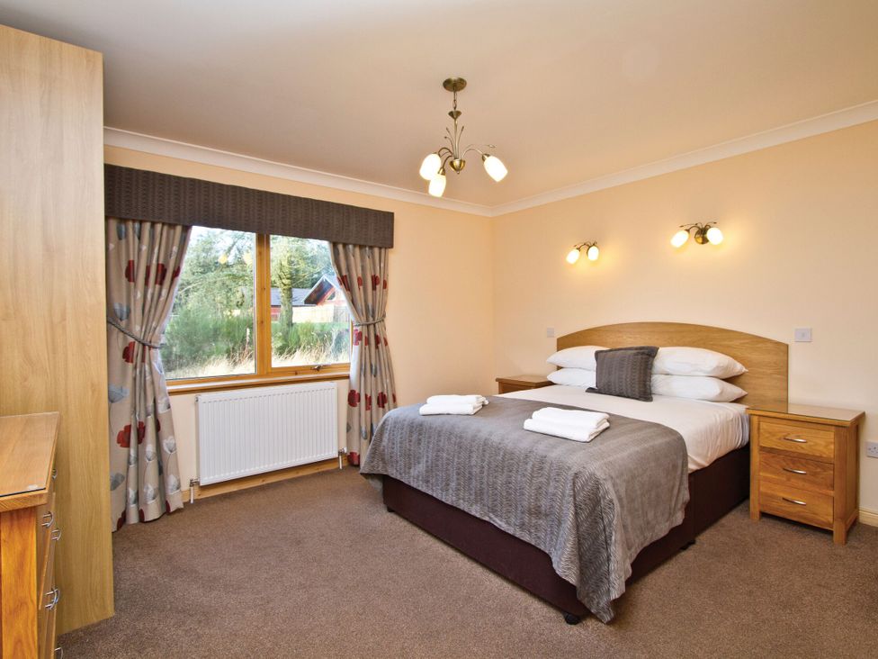 A bedroom with a bed and wardrobe at Osprey Spa Plus in Dundee