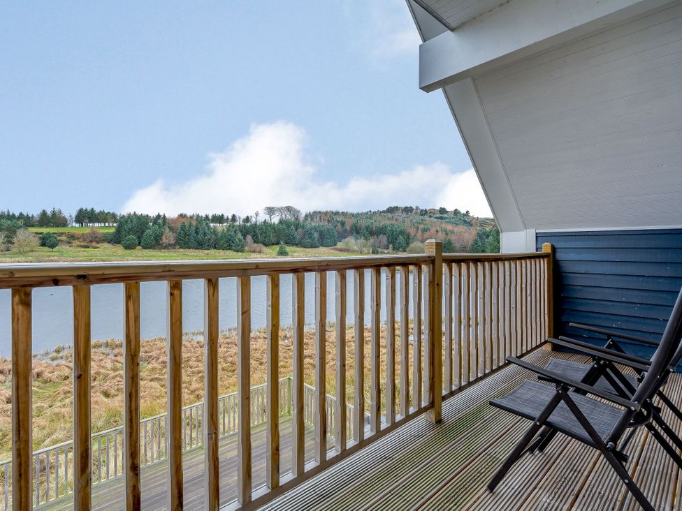 A balcony with chairs overlooking a lake at Lochside Premier Spa in Dundee