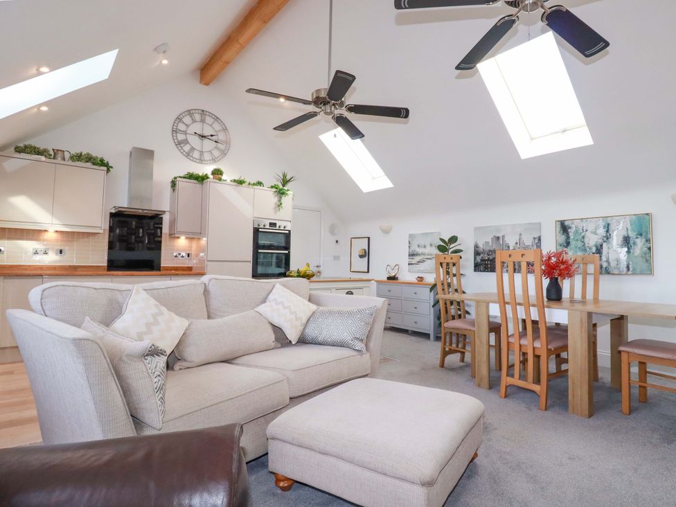 A living room with a sofa, dining table and kitchen cabinets at 33 Fordh Tobmen in St. Agnes