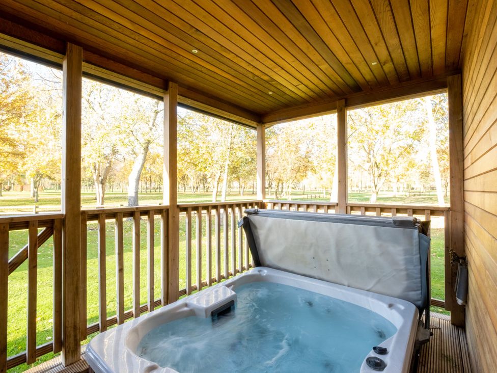An outdoor area with a hot tub on a wooden deck at Belfry in Waltham