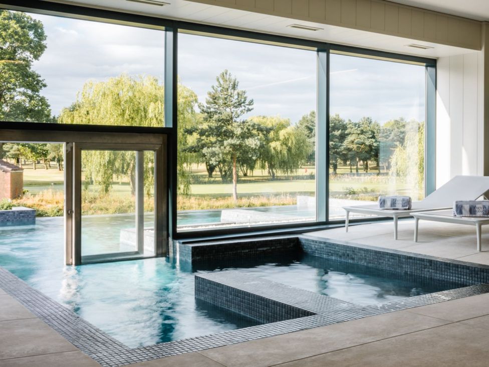 An indoor pool with large windows and a sun lounger at Goldfinch in Waltham