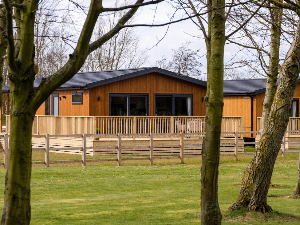 A house with a deck and fence surrounded by grass at Imperial View in Waltham
