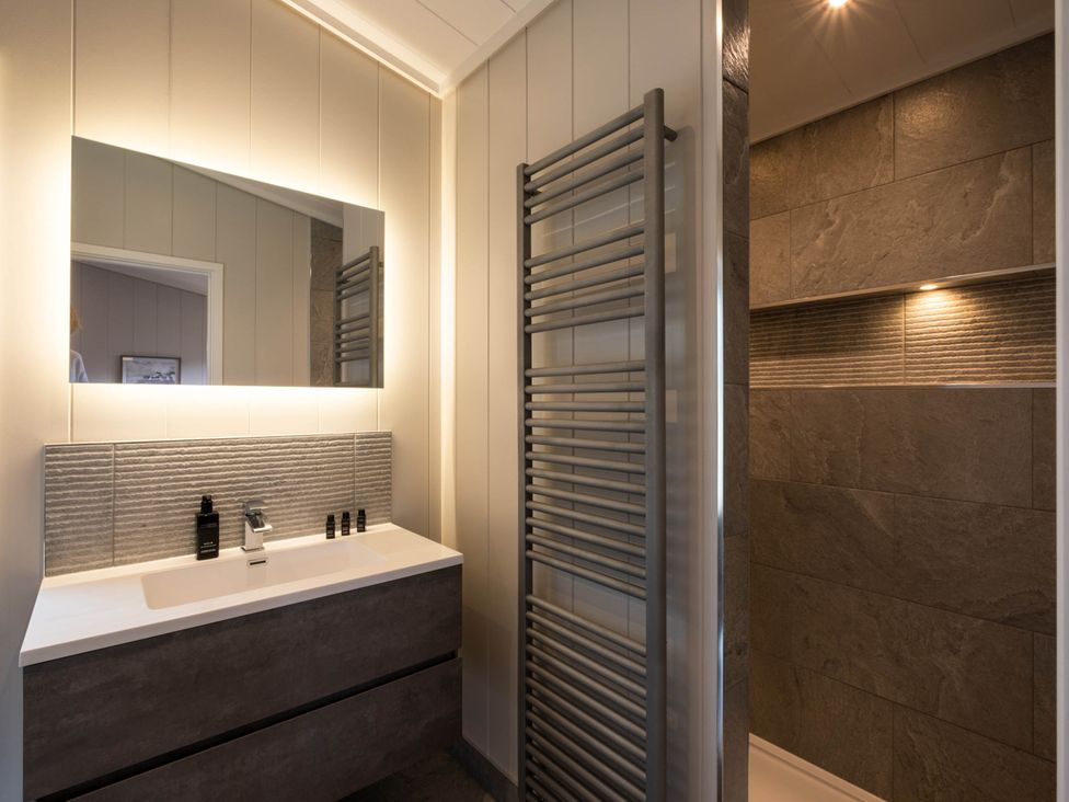A bathroom with sink, mirror, towel radiator, and shower at The Luxury Hideaway in Waltham