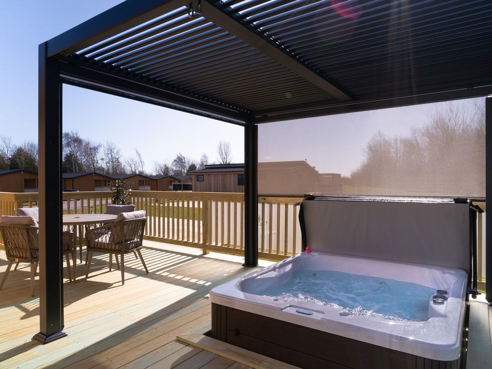 An outdoor deck with a hot tub and seating at The Luxury Hideaway in Waltham