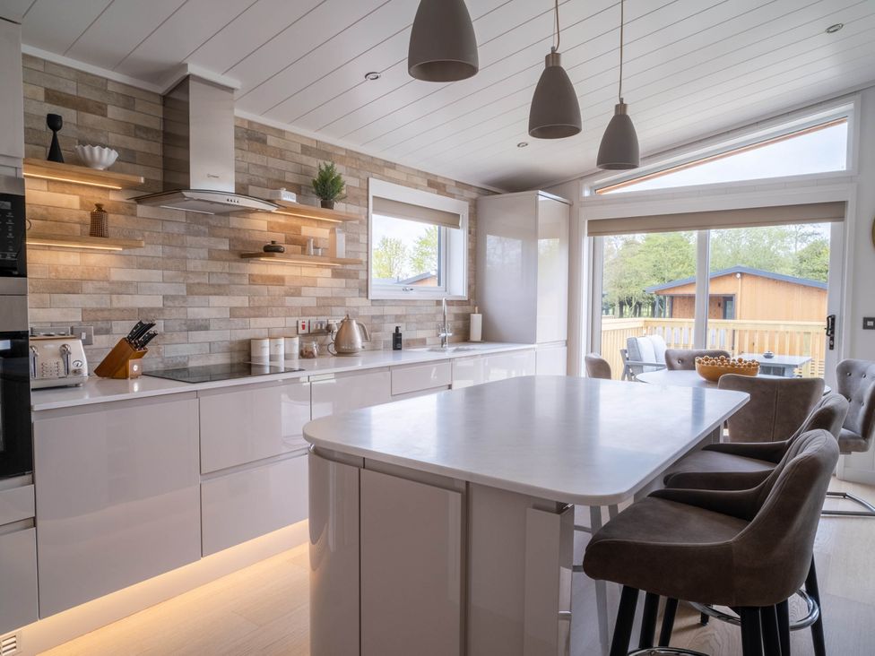 A kitchen with modern appliances and a window overlooking a patio at The Luxury Escape in Waltham