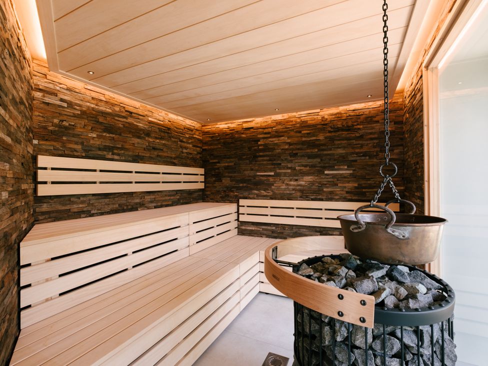 A sauna with wooden benches and a rock heater at The Luxury Escape in Waltham