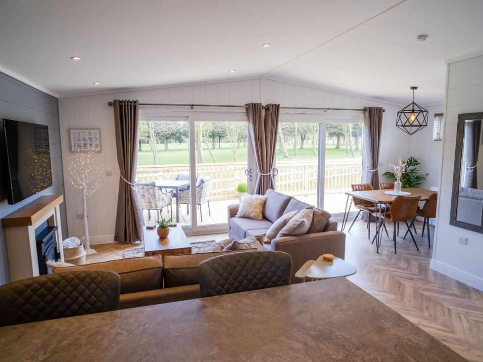 A living room with a dining area and large windows at Dovecote in Waltham