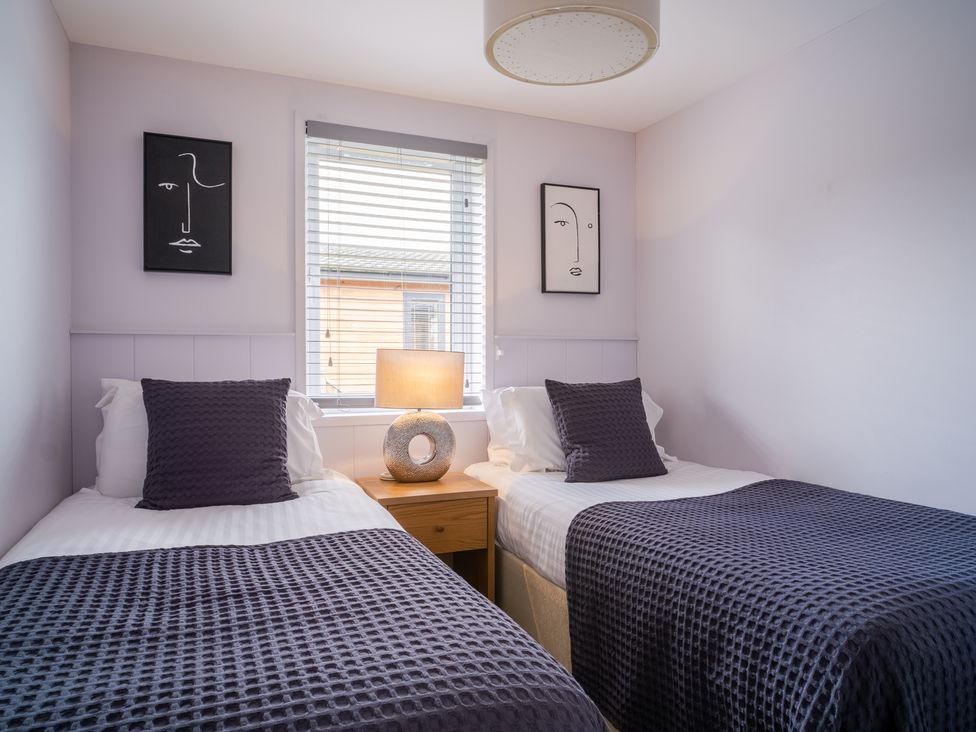 A bedroom with two single beds and a lamp on a nightstand at The View Waltham