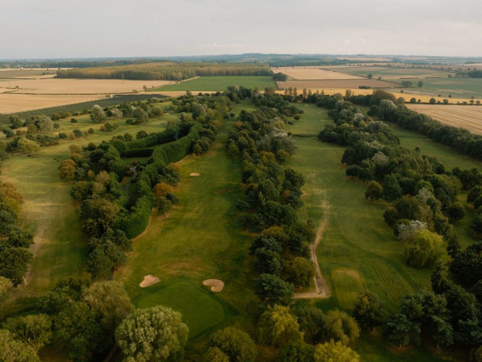 An aerial view of a golf course with trees and open fields at The View in Waltham