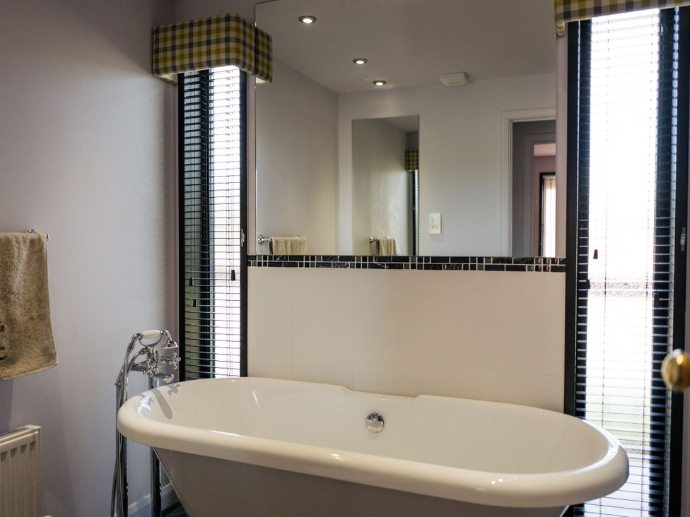 A bathroom with a bathtub and mirror at Macosi in Waltham