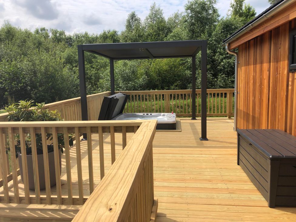 An outdoor deck with a hot tub beneath a canopy at The Luxury Retreat in Waltham