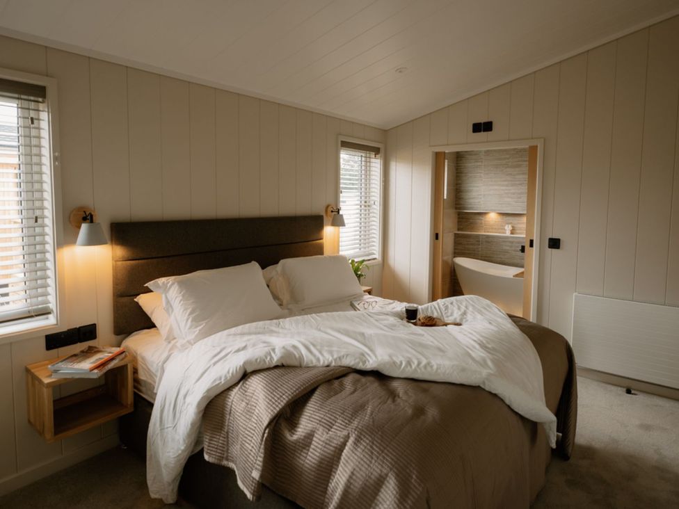 A bedroom with a bed and a bathtub visible in the background at Luxury Boutique Retreat Spa Waltham