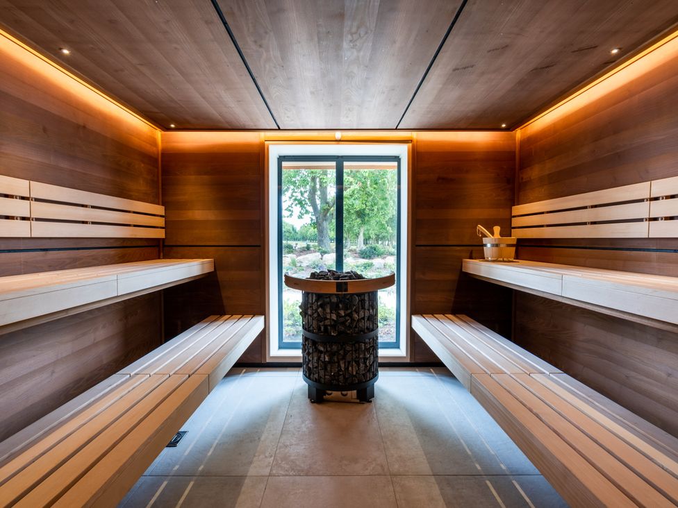 A sauna with wooden benches and a stone heater at Luxury Boutique Retreat in Waltham