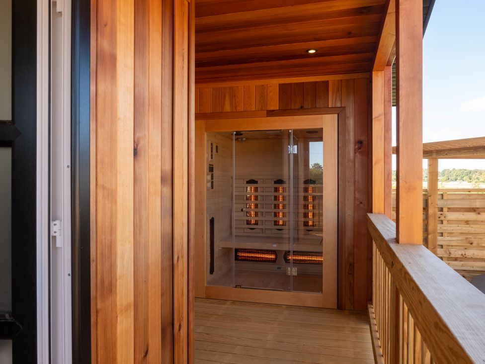 A sauna with wooden walls and a glass door at Exclusive Aura Spa in Waltham