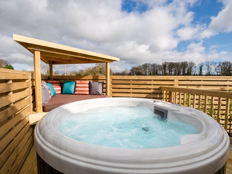 A hot tub with cushions on a wooden deck at Luxury Boutique Retreat Pet in Waltham