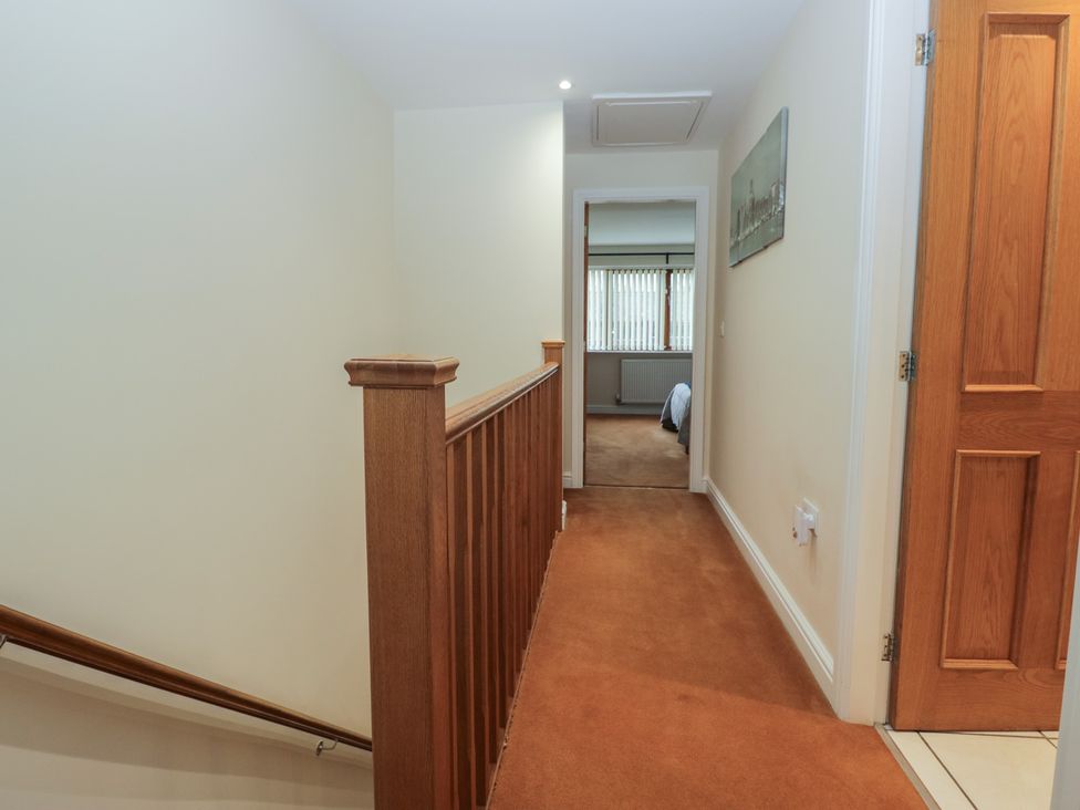 A hallway with brown carpet and wooden railing at 6 Swan House Tewitfield