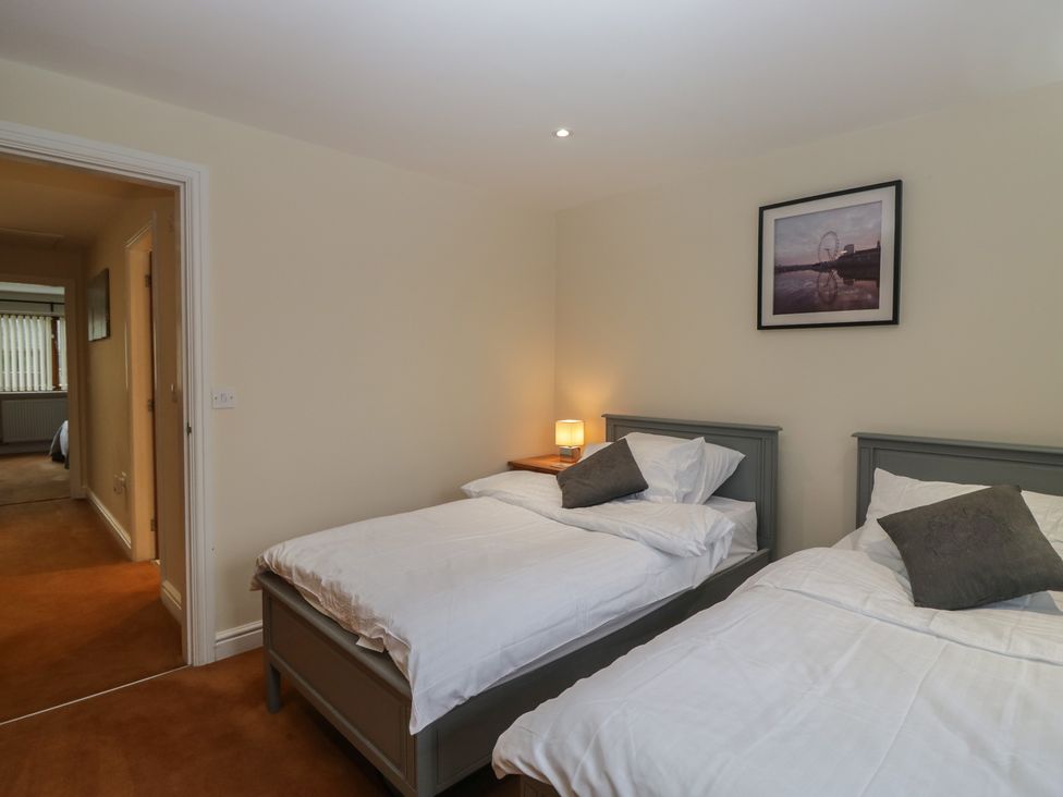 A bedroom with two beds and a lamp at 6 Swan House Tewitfield